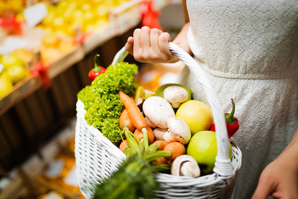 Beautiful young woman shopping vegetables and fruits on the market - 写真・画像