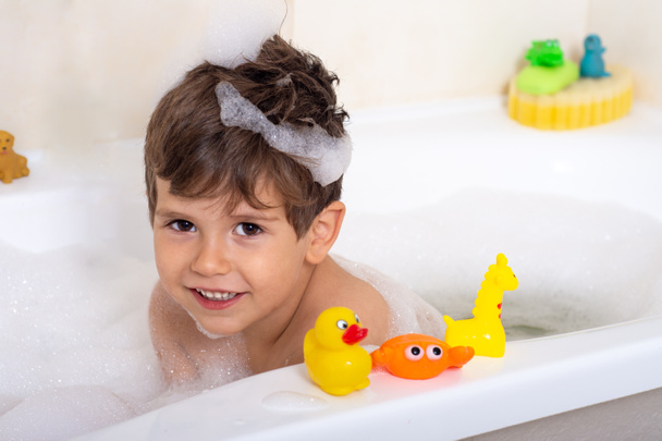 Hygiene for infant and baby. Child playing with soap foam in home bathroom. Rubber duck in foam bath.  - Φωτογραφία, εικόνα