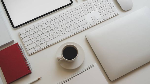 Top kilátás a modern munkahely laptop számítógép, kávéscsésze és egyéb irodai tartozékok fehér asztal háttér  - Fotó, kép