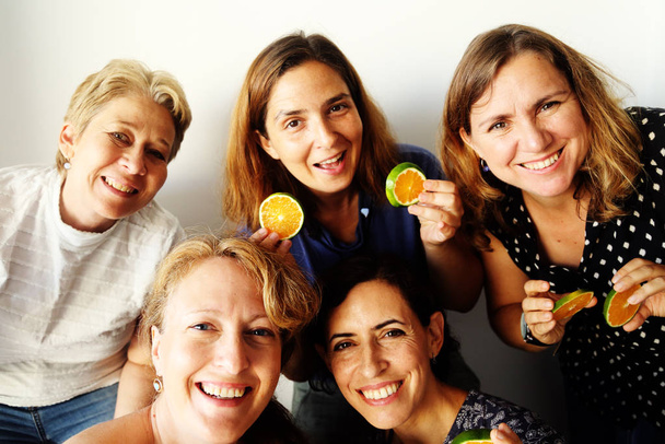 Pět pěkné šťastné dospělé feny s úsměvem a držení čerstvé pomeranče   - Fotografie, Obrázek