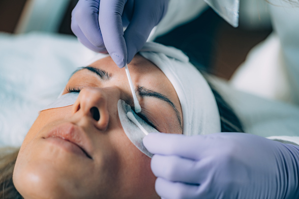 Cosmetólogo de limpieza de los ojos de las mujeres después del procedimiento de elevación de pestañas
  - Foto, Imagen