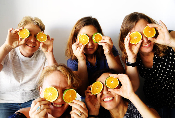 Cinco agradables hembras maduras felices sonriendo y sosteniendo naranjas frescas
   - Foto, Imagen
