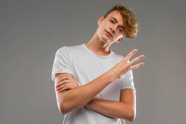 handsome emotional teenager posing in studio against gray  - Foto, afbeelding