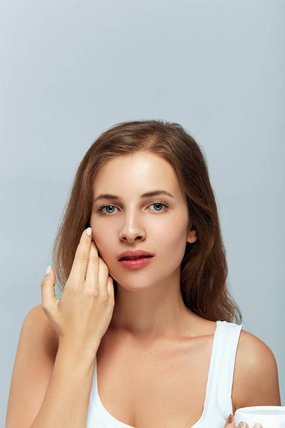 Beauty woman Facial Care. Female Applying Cream. Beauty Face. Portrait Of Young Woman.  CloseUp Of Beautiful Girl With Beauty Product On Soft Skin, Natural Makeup Touching Face. SkinCare - Zdjęcie, obraz