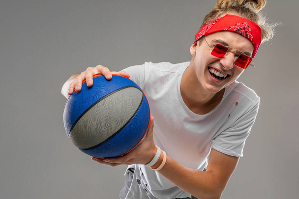 cool tenager boy with ball posing against gray  - Foto, afbeelding