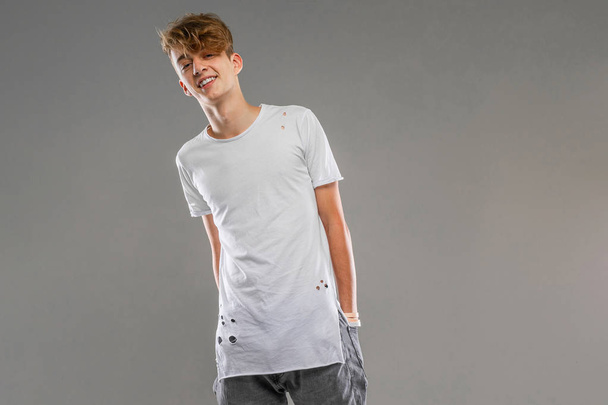 handsome emotional teenager posing in studio against gray  - Fotoğraf, Görsel