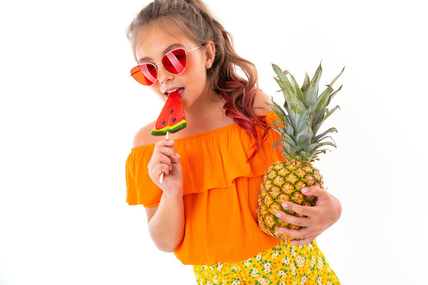 aranyos kislány pózol gyümölcsökkel szemben fehér háttér   - Fotó, kép