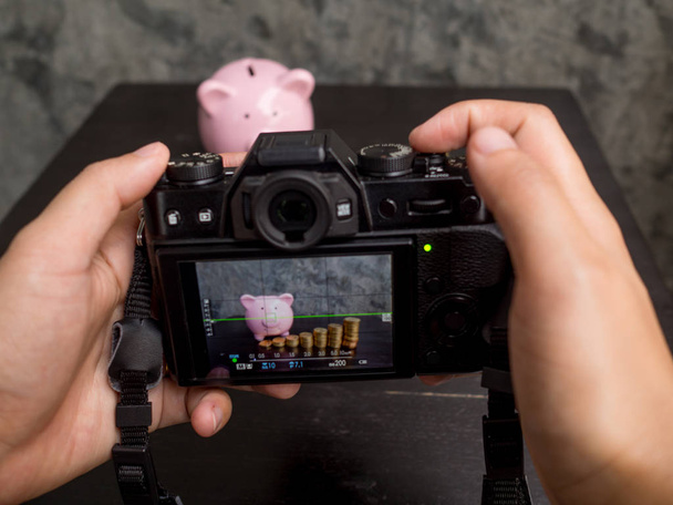 Fotograf zamierza użyć aparatu cyfrowego zrobić zdjęcia różowej świnki bank z wykresem słupków monet - Zdjęcie, obraz