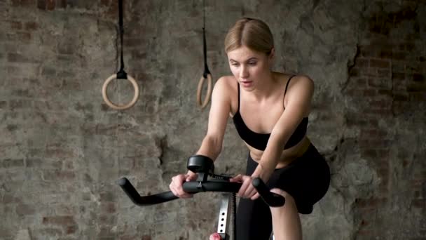 Atractiva mujer fitness montar bicicleta estática en el gimnasio. Un plano medio de una dama delgada en bicicleta. Atleta femenina haciendo ejercicio intenso en bicicleta de gimnasio
 - Imágenes, Vídeo