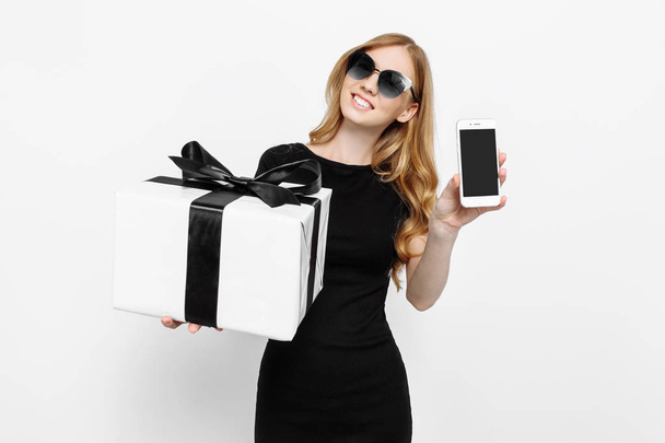 An attractive young girl in a black dress holding a gift with a  - Фото, зображення