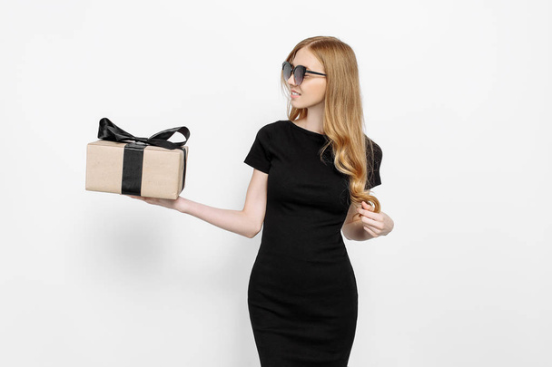 Happy young girl in black dress and sunglasses looking at gift a - Foto, imagen