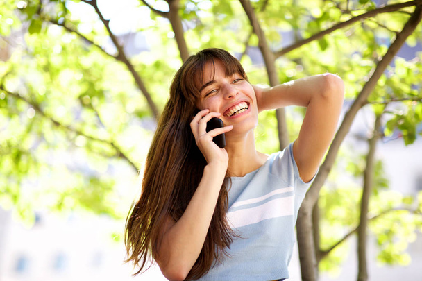 Close up portrait of beautiful smiling young woman talking with phone in park - Φωτογραφία, εικόνα