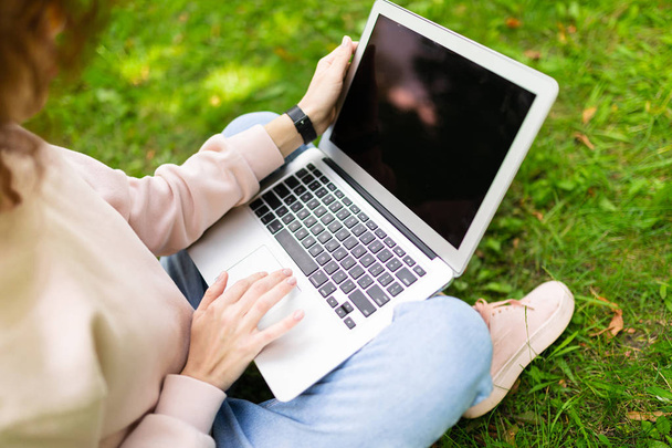 girl working on laptop outdoors sitting on the grass  - Fotoğraf, Görsel