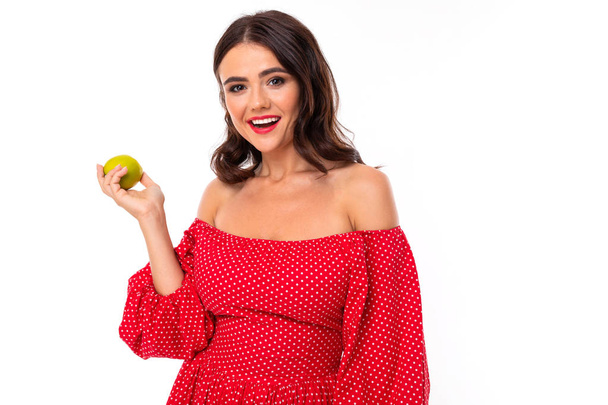 Frau im roten Kleid posiert mit Apfel vor weißem Hintergrund   - Foto, Bild