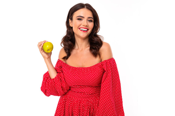 Frau im roten Kleid posiert mit Apfel vor weißem Hintergrund   - Foto, Bild