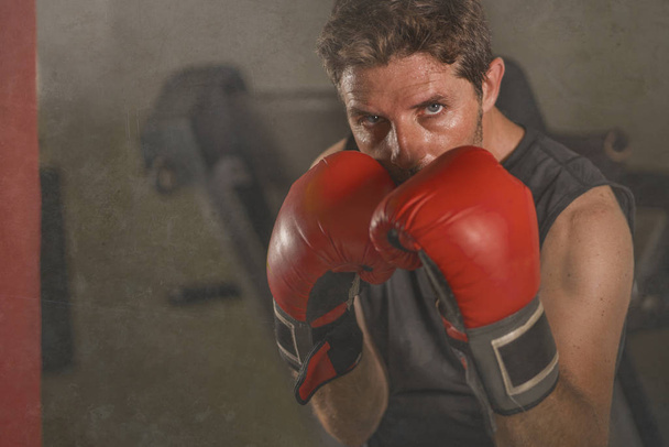 portrait d'entraînement de gymnase de boxeur attrayant et féroce homme de 30 à 40 ans dans la formation de gants de boxe au club de fitness punching sac lourd dans un look badass cool
 - Photo, image