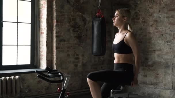 Attractive fitness woman riding exercise bike in gym. Medium shot of slim lady on bike. Female athlete doing intense workout on gym bike - Footage, Video
