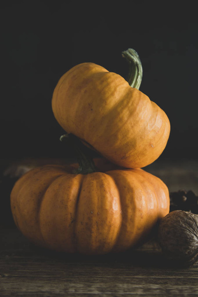 Orange littlep pumpkins on dark wooden background deep shadows, rustic style halloween, thanksgiving, autumn - Foto, Imagem