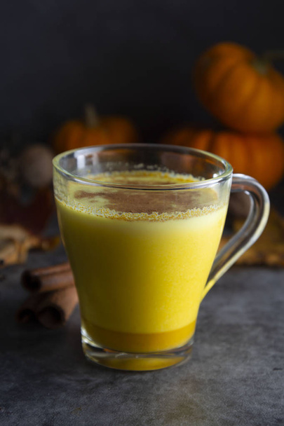 Pumpkin spiced latte macchiato on a dark wooden background autumn drink beverage golden milk - Foto, Bild