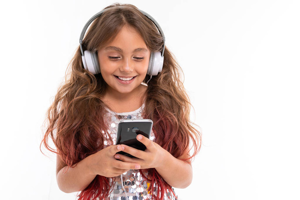 krásná dívka pózuje se sluchátky a mobilní telefon na bílém pozadí - Fotografie, Obrázek