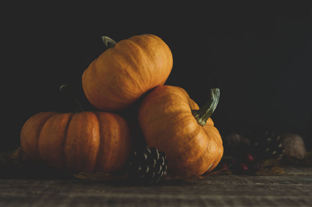 Orange littlep pumpkins on dark wooden background deep shadows, rustic style halloween, thanksgiving, autumn - Photo, image