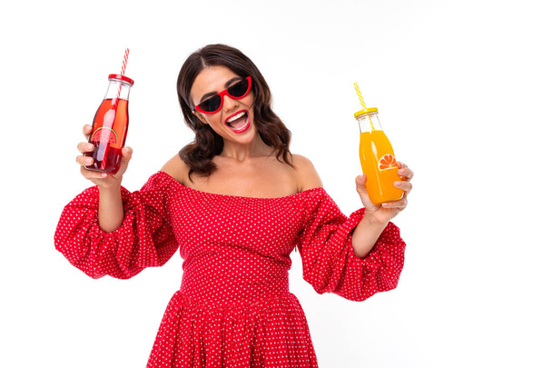 Woman in red dress posing with beverage against white background  - Foto, Imagen