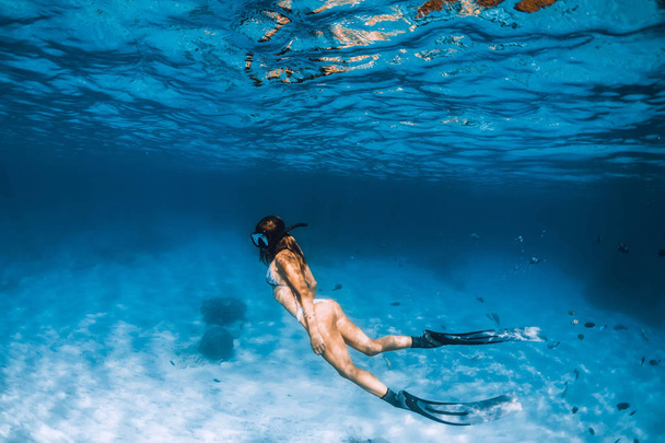Svobodná dívka s ploutvemi klouzá přes písečné dno oceánu - Fotografie, Obrázek