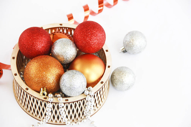 新年の休日のための装飾的な木製のバスケットで光沢のある多色のクリスマスボールのおもちゃ - 写真・画像