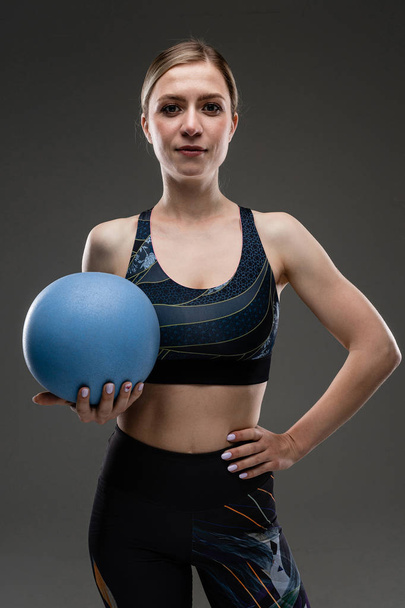 Schöne Sportlerin posiert gegen Grau  - Foto, Bild
