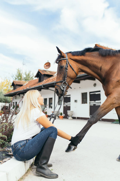Όμορφη νεαρή γυναίκα απολαμβάνει στο ράντσο με το άλογό της.  - Φωτογραφία, εικόνα