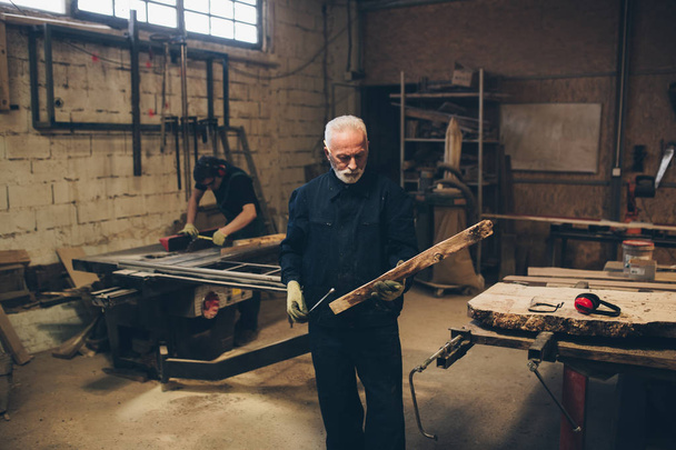 Ανώτερος ξυλουργός πλοίαρχος εργάζεται στην ξυλουργική ή το εργαστήριό του. - Φωτογραφία, εικόνα