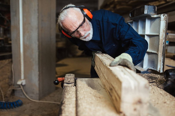 Mestre carpinteiro sênior trabalhando em sua madeira ou oficina
. - Foto, Imagem
