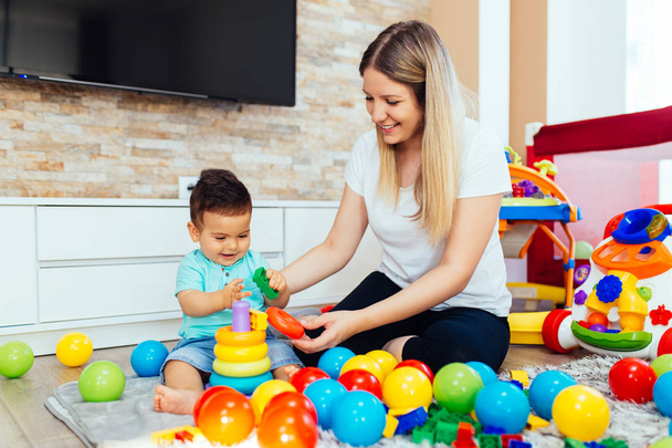 Fiatal és boldog anya játszik a házban a kisfiával - Fotó, kép