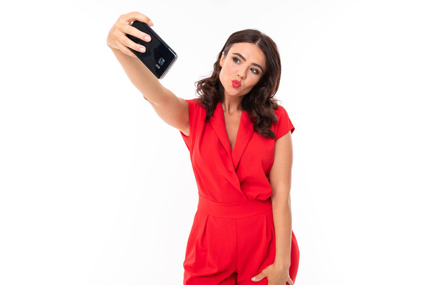 Woman in red dress posing with mobile phone against white background  - Zdjęcie, obraz