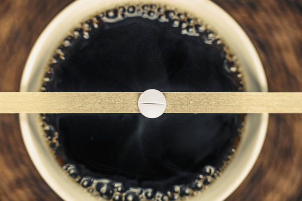 Filiżanka czarnej kawy i kofeina pigułki na drewnianej łyżce  - Zdjęcie, obraz