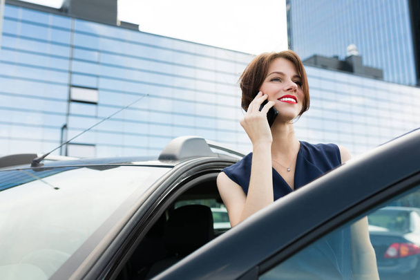 beautiful woman talking on the phone near car  - Foto, imagen