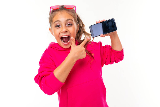 schattig klein meisje poseren mobiele telefoon tegen witte achtergrond   - Foto, afbeelding