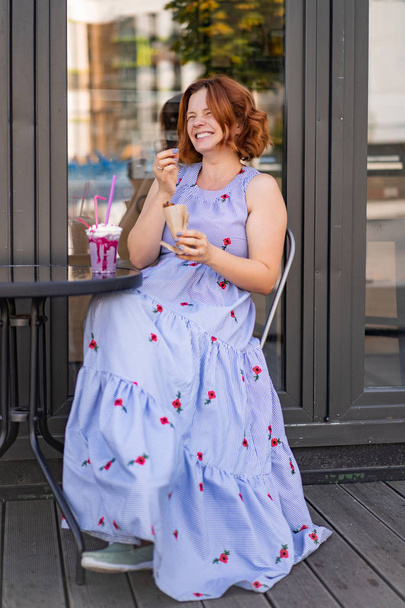 woman with red hair in a cafe drinks a summer cocktail, happy, laughs, smiles. - Foto, Imagem