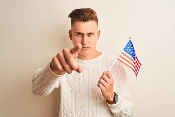 Nuori komea mies, joka pitelee USA:n lippua valkoisella pohjalla osoittaen sormella kameraa ja sinua, käsimerkki, positiivinen ja itsevarma ele edestä
 - Valokuva, kuva