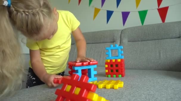 Female child connecting colorful constructor parts on sofa. Gimbal motion - Кадры, видео