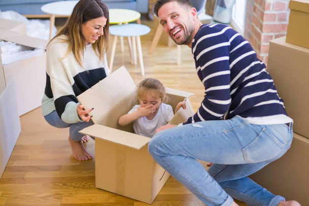 Hermosa familia, niño jugando con sus padres montar caja de cartón en el nuevo hogar
 - Foto, Imagen