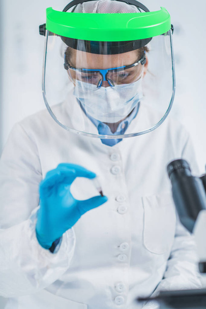 Análise de ADN antiga. Cientista feminina segurando micro tubo com amostra em laboratório de DNA antigo
 - Foto, Imagem