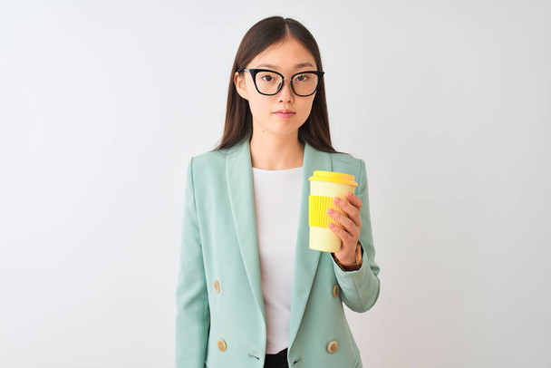 Young chinese woman wearing glasses drinking coffe over isolated white background with a confident expression on smart face thinking serious - Fotografie, Obrázek