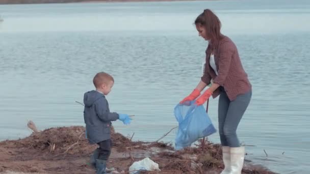 stop pollution, woman volunteers with little child boy clean dirty coast from plastic trash on river waterfront - Footage, Video