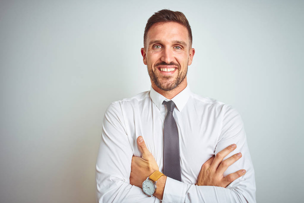 Νέος όμορφος επιχειρηματίας φορώντας κομψό λευκό πουκάμισο πάνω από απομονωμένο φόντο χαρούμενο πρόσωπο χαμογελώντας με σταυρωμένα χέρια κοιτάζοντας την κάμερα. Θετικό πρόσωπο. - Φωτογραφία, εικόνα
