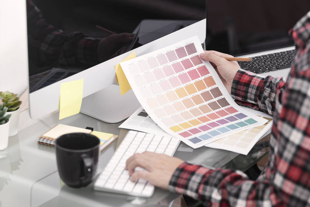 グラフィックデザイナーのアーティストがオフィスのデスクでカラーチャートを見てクリエイティブ. - 写真・画像
