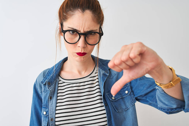 Redhead woman wearing denim shirt and glasses standing over isolated white background with angry face, negative sign showing dislike with thumbs down, rejection concept - Foto, Bild