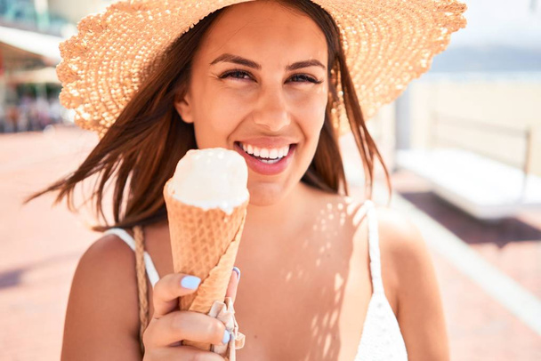 Молода красива жінка їсть морозиво на пляжі в сонячний день літа на канікулах
 - Фото, зображення