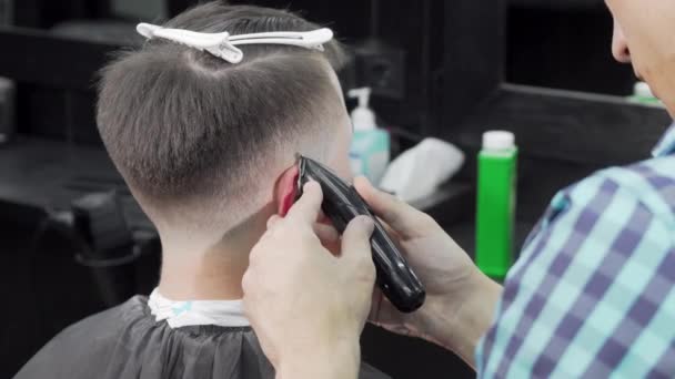 Professional barber giving a haircut to a male customer - Imágenes, Vídeo