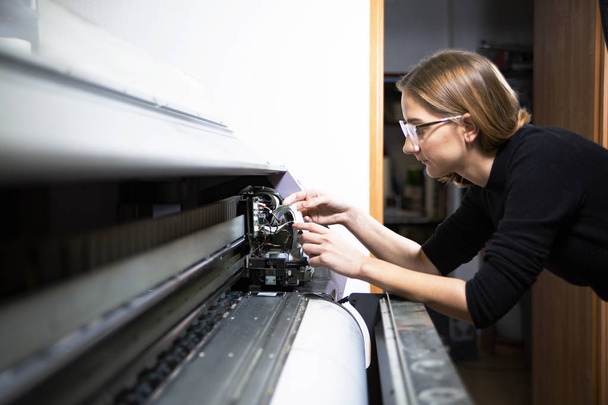 Printing house. The employee operates the printing machine - Фото, изображение
